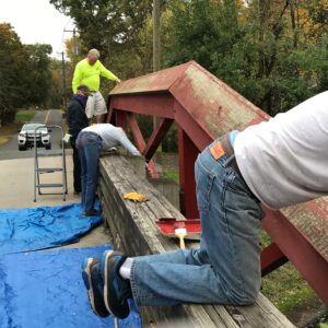 Volunteers paint a camelback bridge. bridge.